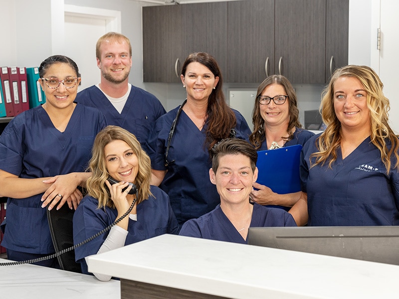 smiling nurses gathered behind the nurse's station desk