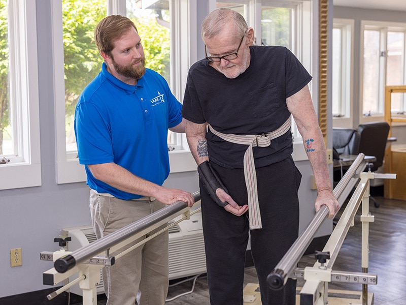 physical therapist assisting elderly resident during physical therapy exercise